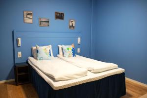 a blue room with a bed with white sheets and pillows at Scandic Vulkan in Oslo