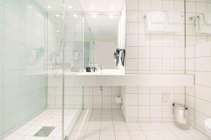 a white bathroom with a sink and a shower at Scandic Vulkan in Oslo
