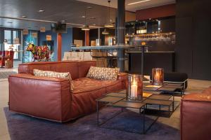 a living room with a brown couch and two tables at Scandic Vulkan in Oslo