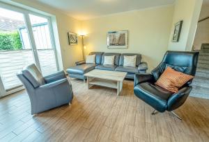 Una sala de estar con dos sillas y un sofá. en Ferienhaus Niedertor, en Bensersiel