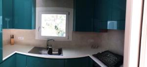 a kitchen with green cabinets and a sink and a window at Blue Eden La Maddalena in La Maddalena +77 photos