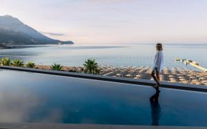 a woman walking on the edge of a swimming pool overlooking the ocean at Sea Star Budva in Budva +37 photos