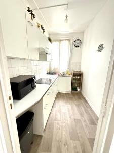 a kitchen with white cabinets and a black microwave at Balcon de Paris in Gennevilliers