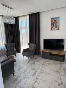 a living room with a flat screen tv and chairs at Aurum Villas Smokinya Beach in Sozopol