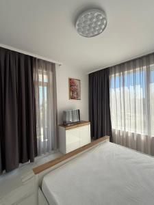 a bedroom with a bed and two large windows at Aurum Villas Smokinya Beach in Sozopol