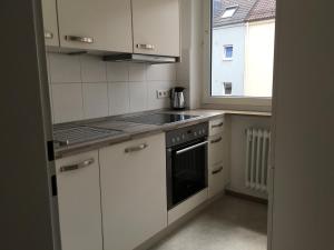 una cucina con armadietti bianchi, piano cottura e finestra di Vida Real Estate Nürnberg a Norimberga