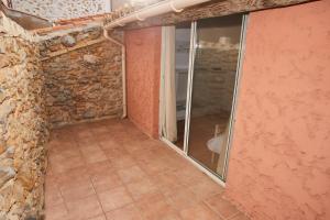 a room with a stone wall and a glass door at Chambre dans maison de village in Fitou