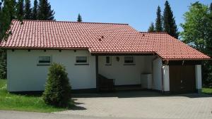 una pequeña casa blanca con techo rojo en Ferienhaus Fuchsweg im Feriendorf Reichenbach F4, en Nesselwang