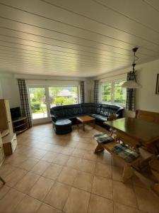 Una sala de estar con un sofá negro y una mesa. en Ferienhaus Fuchsweg im Feriendorf Reichenbach F4, en Nesselwang 11 fotos más