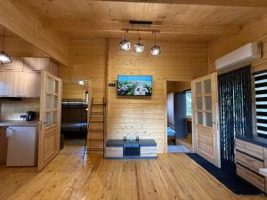 a room with a kitchen and a tv on the wall at Domki nad jeziorem Lubie in Gudowo +39 photos