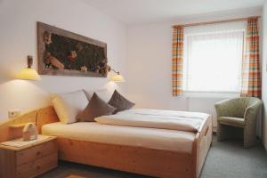 a bedroom with a bed and a chair and a window at Ferienhaus Ahorn in Neustift im Stubaital