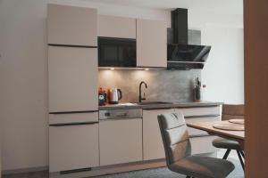 a kitchen with white cabinets and a wooden table at Ferienhaus Ahorn in Neustift im Stubaital