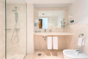 a bathroom with a shower and a sink and a mirror at Hipotels Playa La Barrosa - Adults Only in Chiclana de la Frontera