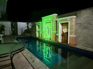 a swimming pool with green lighting in a building at Emerald hotel in Jomtien Beach
