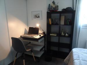 a desk with a laptop and a chair in a room at Le jardin de Brigitte in Vergeroux