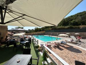 an outdoor swimming pool with tables and chairs and umbrellas at Cuccumiao in Sorgono