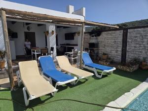 a group of chairs on a lawn next to a pool at Chalet rural a las afueras de Montellano in Montellano
