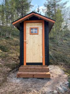 a out house with a wooden door in a field at Villa Aiku in Leppäjärvi