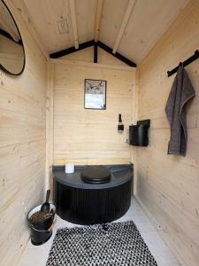 a sauna with a black toilet in a wooden wall at Villa Aiku in Leppäjärvi