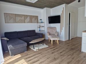 Una sala de estar con un sofá azul y una silla. en Domki na Wypasie - Jaworki, en Jaworki