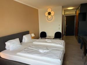 ein Hotelzimmer mit zwei Betten und zwei Stühlen in der Unterkunft Skycity Hotel Atrigon in Klagenfurt am Wörthersee