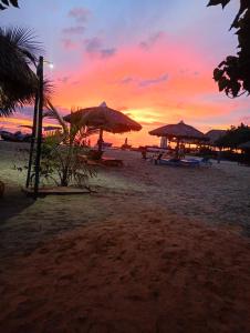 a sunset on a beach with umbrellas and the ocean at Los Clemones in Rincón