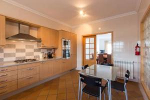 a kitchen with wooden cabinets and a table and chairs at T2 piscina e vista mar Praia del Rey Óbidos A6 in Casal da Lagoa Seca