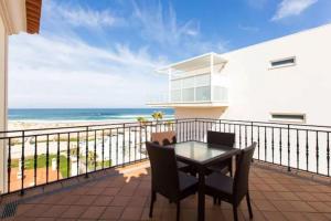 a balcony with a table and chairs and the beach at T2 piscina e vista mar Praia del Rey Óbidos A6 in Casal da Lagoa Seca