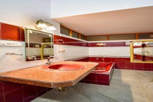 a bathroom with a red sink and mirrors at Hotel O The Nandini's Guest House in Jaipur