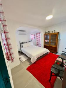 a bedroom with a bed and a red rug at Kıbrıs Evi (Cyprus House) in Mağusa