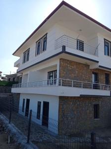 a large white building with a fence in front of it at Spacious and modern apartment with a view in Gökçeada