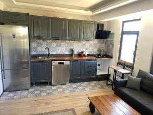 a kitchen with gray cabinets and a couch in a living room at Spacious and modern apartment with a view in Gökçeada