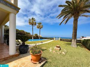 een tuin met palmbomen en een zwembad bij casa frente el mar in Denia