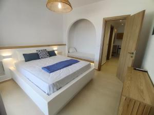 a bedroom with a large white bed with blue pillows at Amodari studios on the beach in Plaka