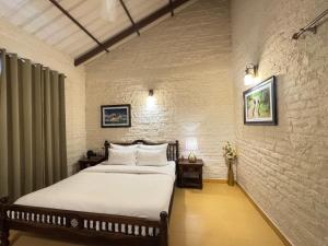 Un dormitorio con una cama y una pared de ladrillo. en The Cliff House, 3BR LUX Villa 2km to Rajpur Road, en Dehradun