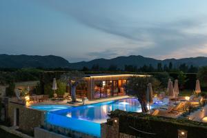 a swimming pool with chairs and umbrellas next to a house at Anthemida Rooms in Sykia Chalkidikis
