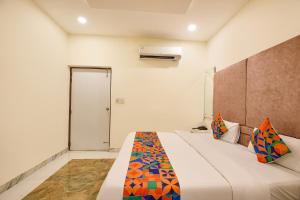 a bedroom with a large white bed with colorful pillows at FabExpress High View in Faridabad