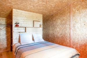 een slaapkamer met een bed met een houten muur bij L'Escale du Dernier Pin in Escalans +16 foto's