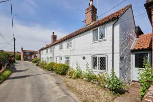 une maison blanche sur le côté d'une rue dans l'établissement Host & Stay - Romney Cottage, à Corpusty