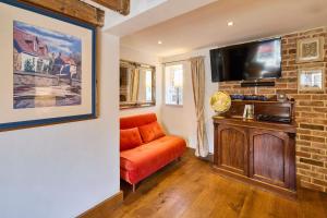 un salon avec un canapé orange et une télévision à écran plat dans l'établissement Host & Stay - Romney Cottage, à Corpusty 13 autres photos