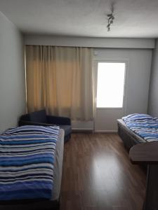 Habitación con 2 camas, sofá y ventana en Tiilipooli10, en Pori