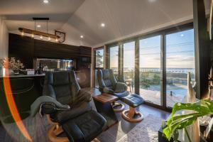 a living room with chairs and a bar with a view at Ocean breeze homestays 1 in Bicheno