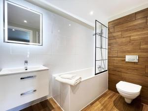 une salle de bain blanche avec toilettes et lavabo dans l'établissement Carleys Yard by The Suffolk Cottage Collection, à Framlingham