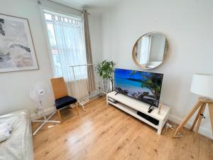 a living room with a tv and a mirror at 11 Guests - 6min Drive to the Wembley Stadium in London