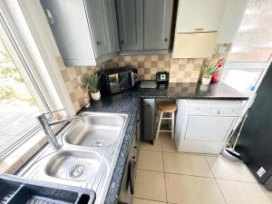 a small kitchen with a sink and a microwave at 11 Guests - 6min Drive to the Wembley Stadium in London +5 photos