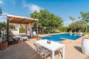 ein Swimmingpool mit einem weißen Tisch und Stühlen neben einem Pool in der Unterkunft Casa Rural Carula in La Puebla de Cazalla