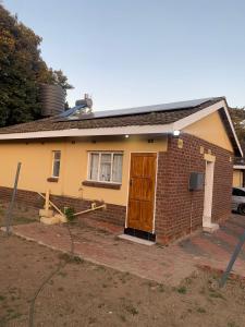 a small brick house with a brown door at Cosy Harare Haven Cottage in Harare