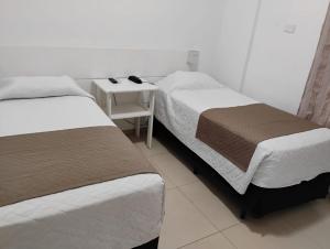 a room with two beds and a table with a night stand at Atlantico Flat Santos in Santos