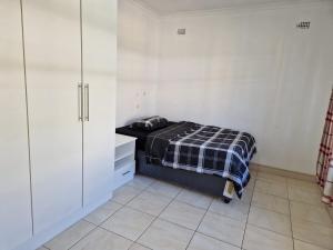 a bedroom with a bed and white cabinets and a tiled floor at Cosy Harare Haven Cottage in Harare