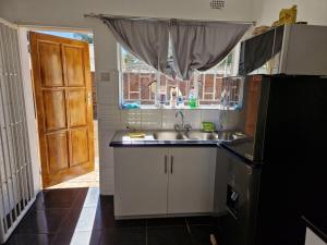 a small kitchen with a sink and a refrigerator at Cosy Harare Haven Cottage in Harare +1 photo